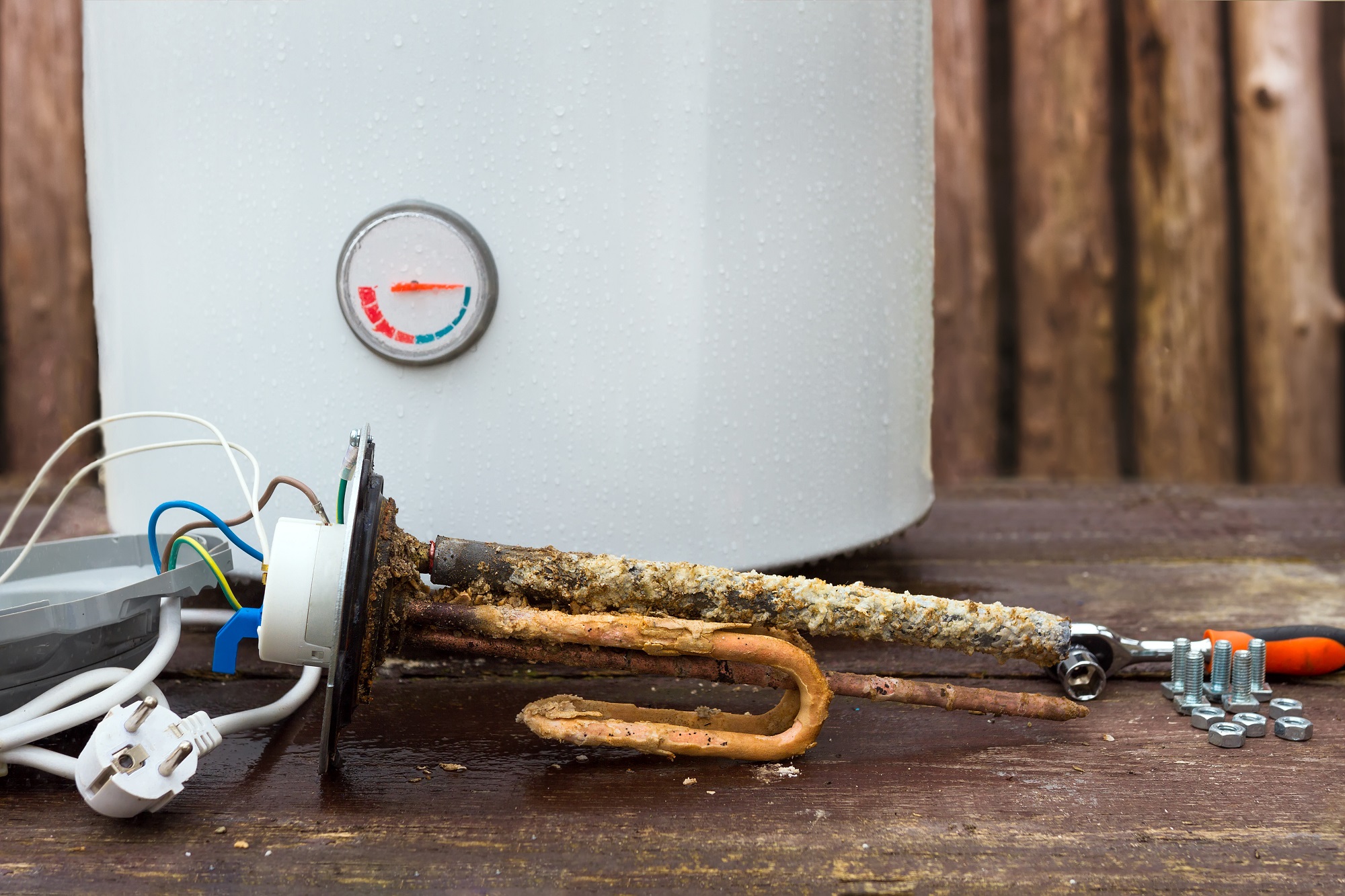 broken water heater with heating elements, on wooden background.